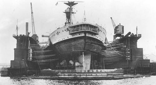 The 'R' class battleship HMS Revenge undergoes a refit in a floating dock during the 1930s